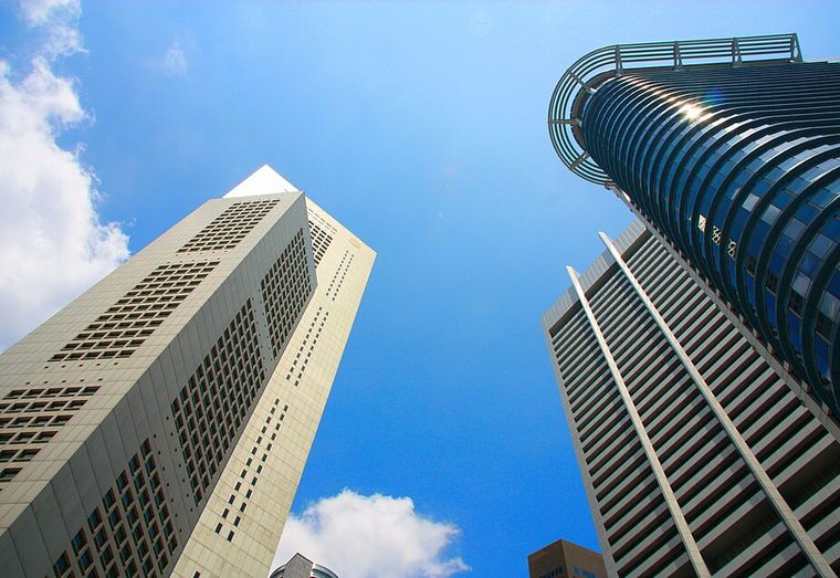 Three skyscrapers converging overhead against blue sky