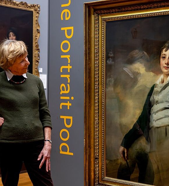 Museum visitor looking at a gold-framed portrait painting