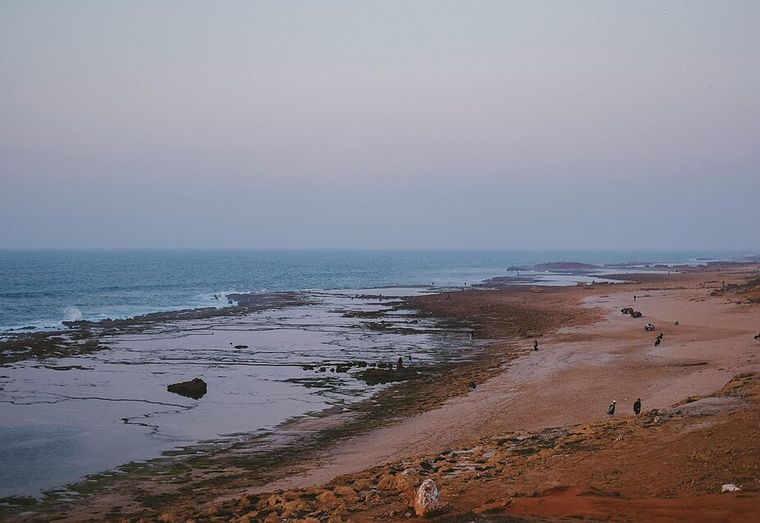 Beach at dusk with the horizon on the top third line and walkers on the right third