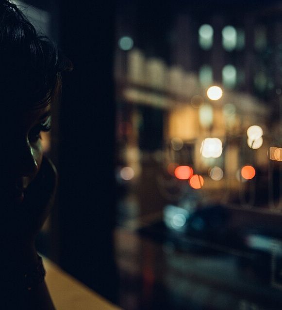 Silhouette at a cafe window at night with street lights as bokeh