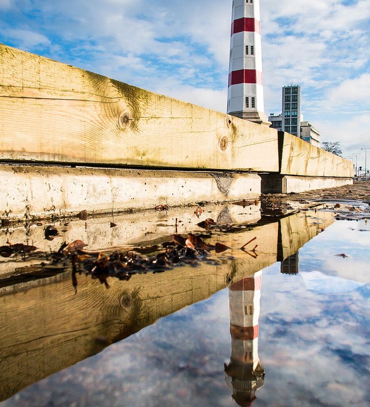 Lighthouse reflected in a puddle shot from water level