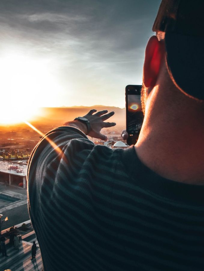 Person holding a camera out at arm's length to take a photo