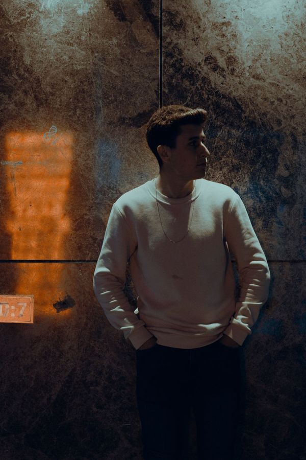 Man leaning against a wall with directional side light falling across half his face