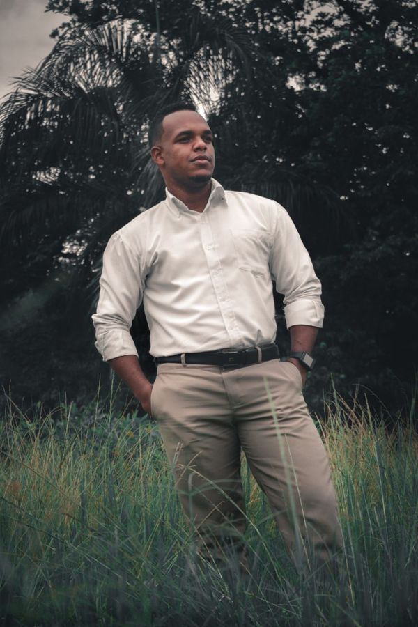 Man standing with hands in his pockets, weight on his back foot, looking off to the side