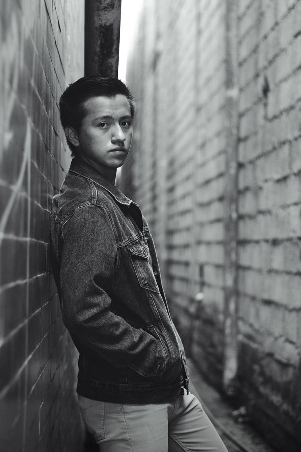 Man turned away then looking back over his shoulder against a brick wall, black and white