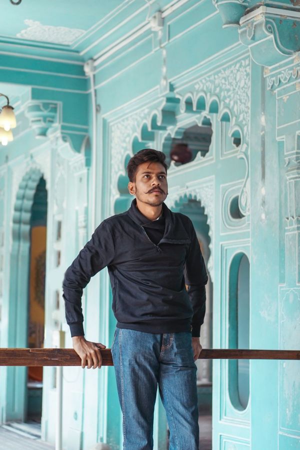 Man leaning on a railing with one hand resting, looking off to the side